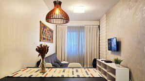 Una sala de estar moderna con una mesa de comedor, sillas, un sofá, un televisor y un jarrón decorativo.