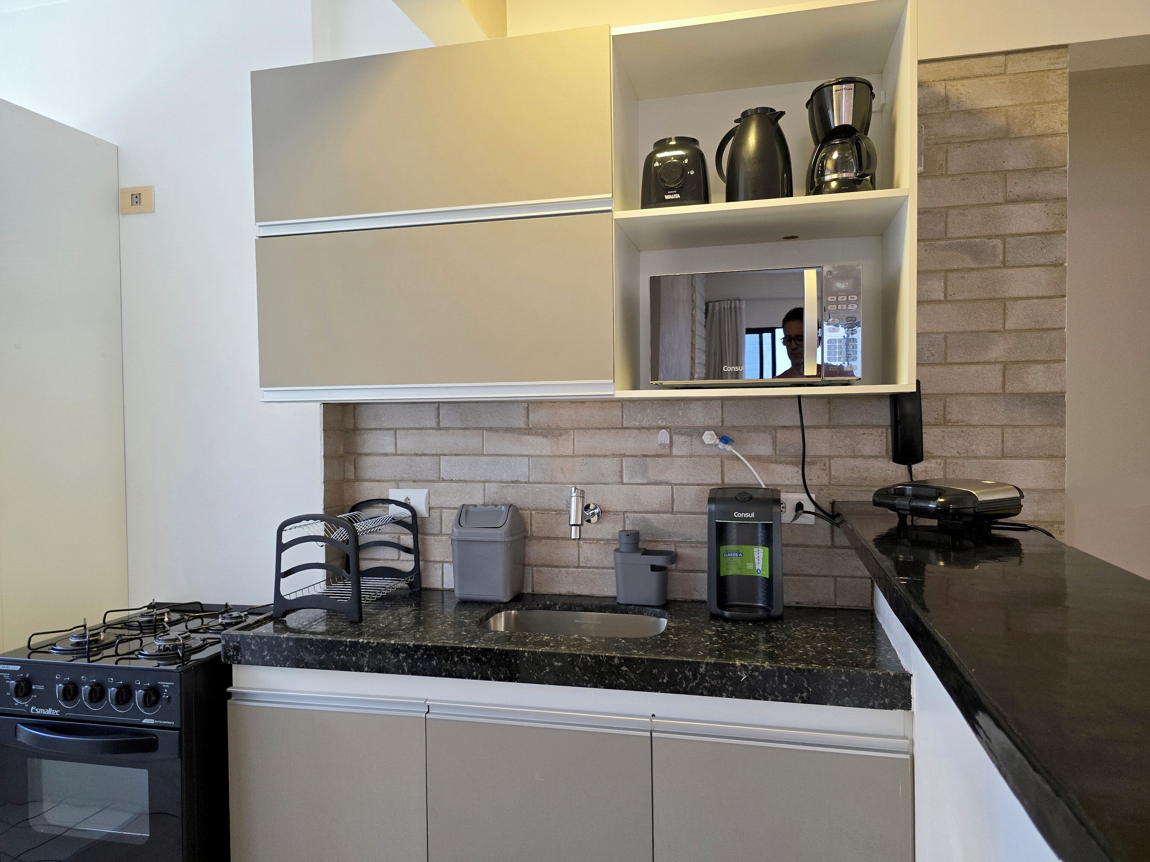 A modern kitchen with a gas stove, a coffee maker, a microwave, and a coffee pot on the countertop.