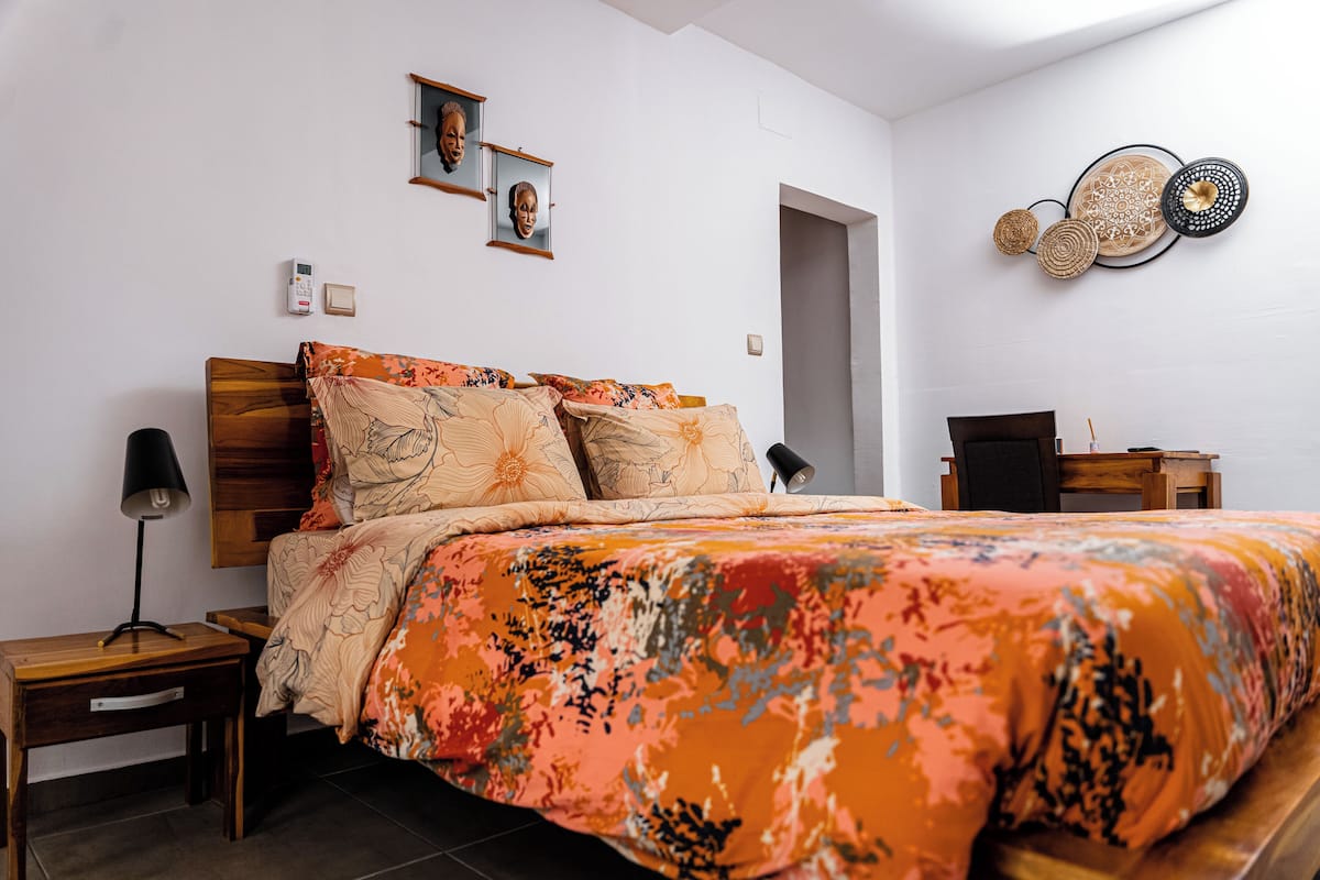 A bedroom with a bed, bedside tables, a desk, and a wall-mounted mirror.