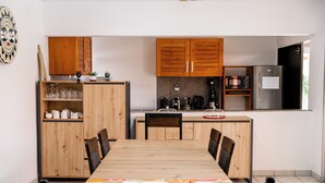 Una cocina moderna con armarios de madera, una mesa de comedor y un refrigerador.