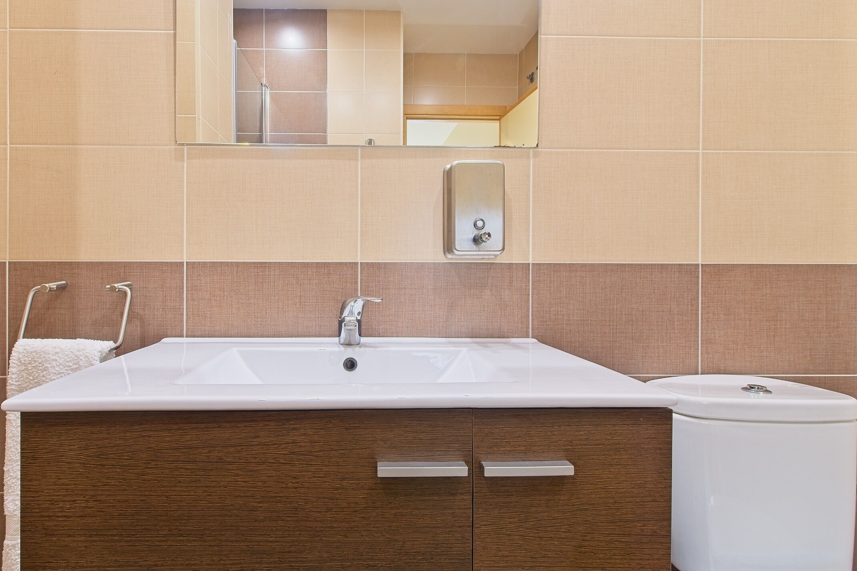 Une salle de bain avec un grand lavabo, un miroir et un meuble en bois.