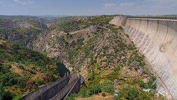 Un grand barrage, avec un terrain escarpé et rocheux, et une rivière en contrebas.