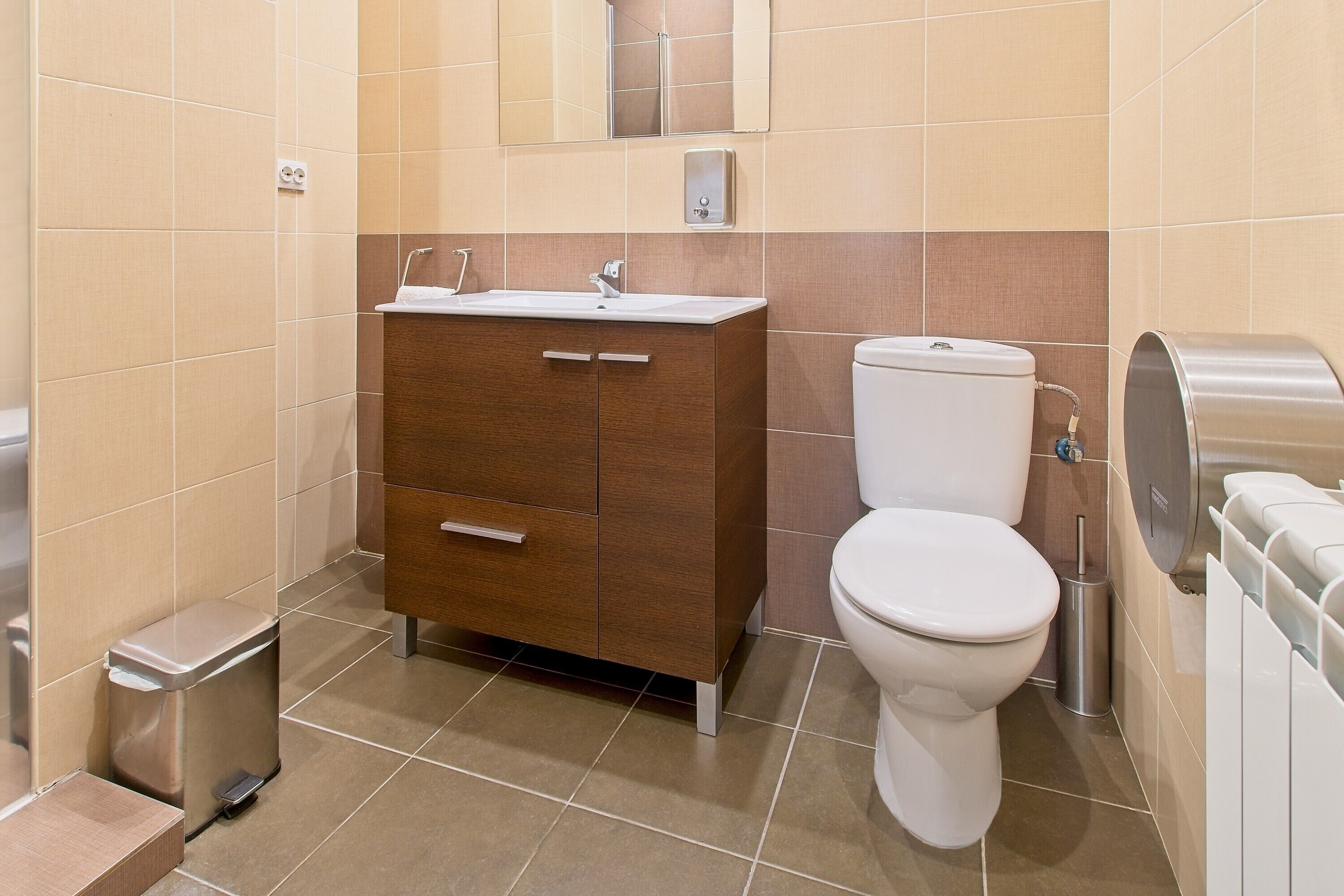 A modern bathroom with a toilet, sink, and cabinet.