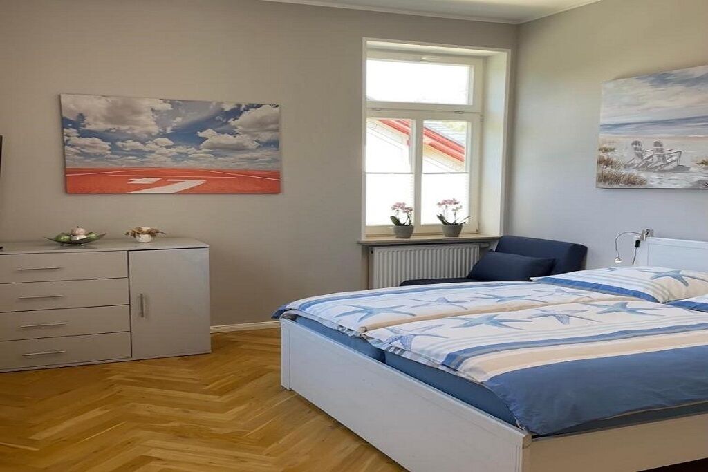 Ein Schlafzimmer mit Bett, Schminktisch, einem Fenster mit Blick und Bildern an den Wänden.