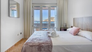 Une chambre d’hôtel avec un lit, une fenêtre avec des rideaux, un miroir et une vue sur l’extérieur.