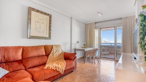 Un salon avec un canapé, une table et un balcon offrant une vue agréable.