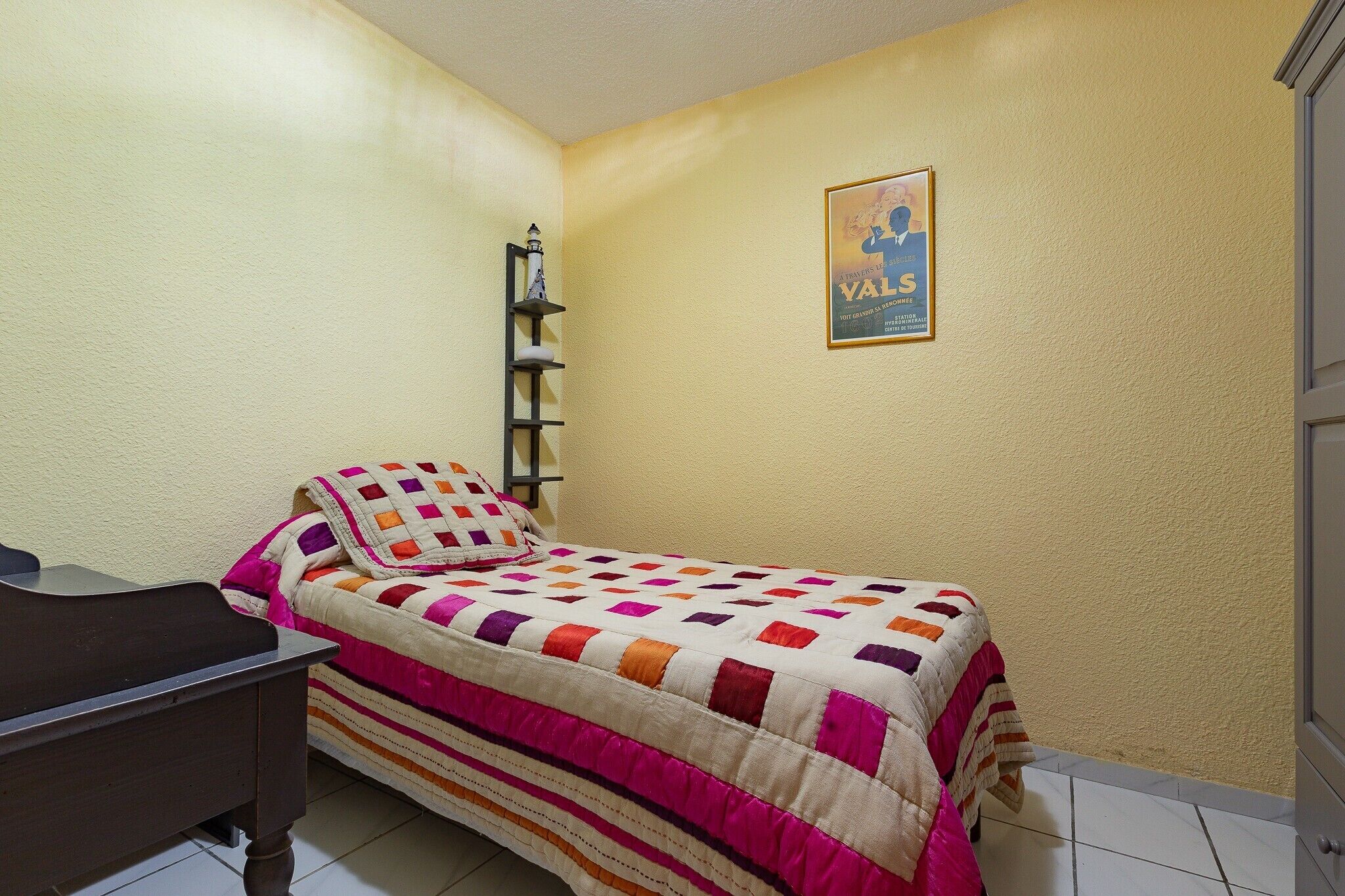 Ein Schlafzimmer mit einem Bett, einem Nachttisch, einer Wandregal und einem Poster an der Wand.