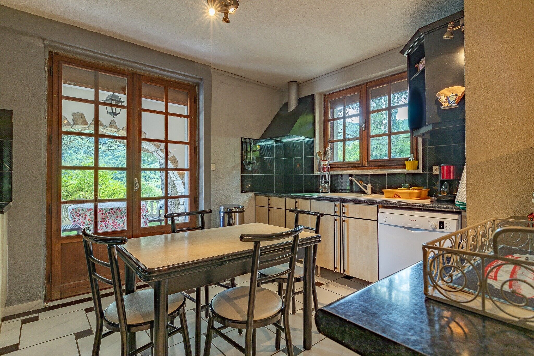 Una cocina con una mesa de comedor, sillas, lavavajillas y una ventana con vistas a zonas verdes.