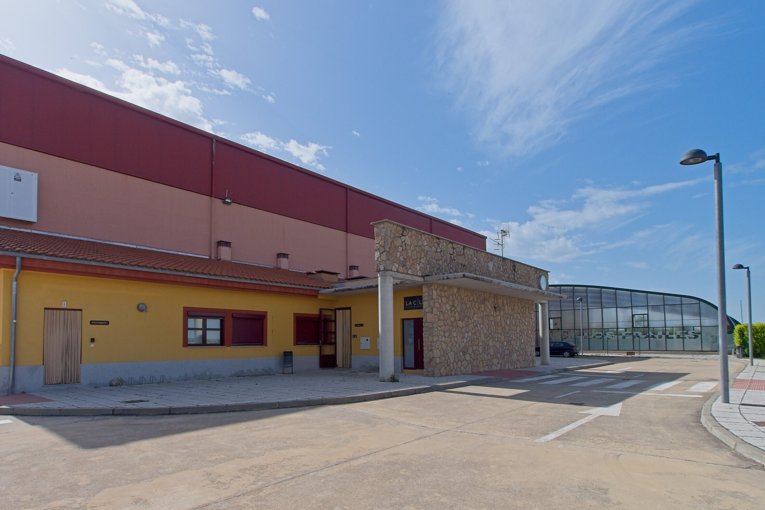 Un bâtiment à la façade jaune, de construction en pierre, et doté d’une grande entrée en verre.