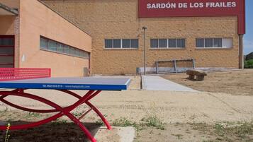 En bygning med et skilt, der viser 'PISCINAS CENTRO RECREATIVO SARDÓN DE LOS FRAILES', og et ping pong-bord i forgrunden.