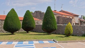Un estacionamiento con marcas azul y blanco a rayas, el símbolo de accesibilidad para sillas de ruedas y árboles cónicos cuidadosamente podados.