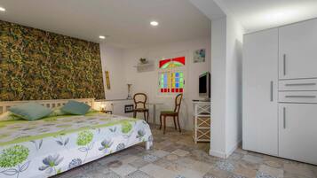 Un dormitorio con cama, escritorio, silla, armario y una pared con estampado floral.
