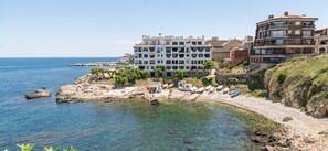 A coastal hotel with multiple balconies, a rocky shoreline, and boats. - Holiday Home Valerie (L'Escala)