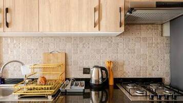 Una cocina con armarios de madera, estufa a gas, cafetera y escurreplatos.
