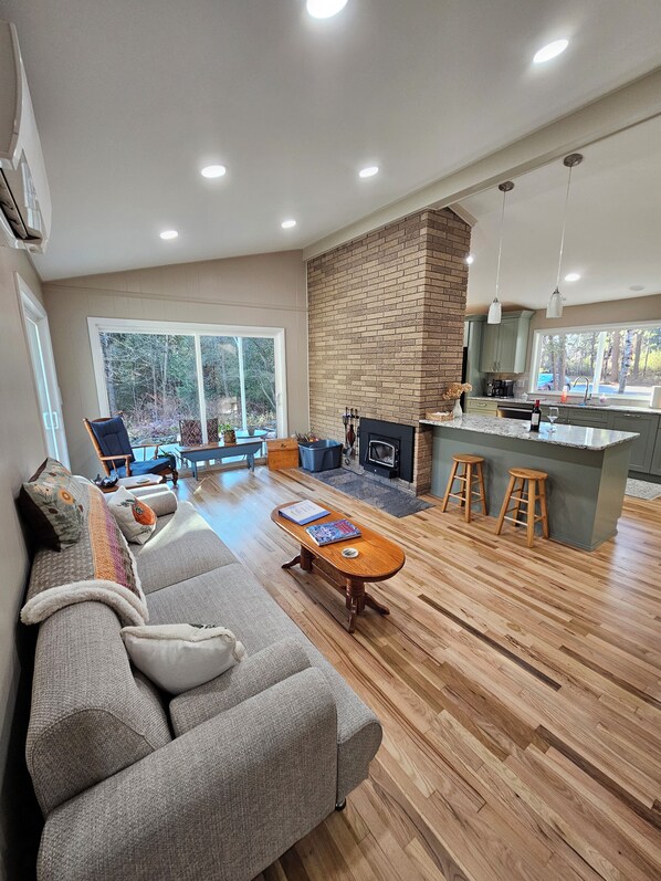 A spacious living area with a fireplace, a sofa, and a dining area with stools.
