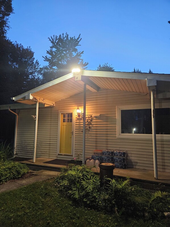 A house with a covered porch, a yellow door, and a window.
