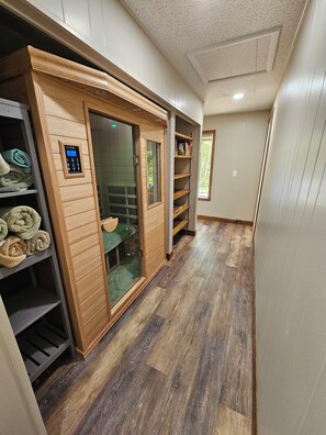 A hallway with a sauna, wooden shelves with towels, and a window with a view.