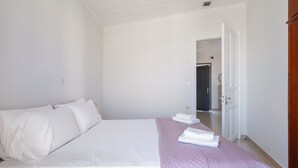 A bedroom with a bed, a door, and a hallway.
