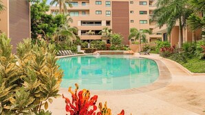Ein Hotel mit Pool, umgeben von Palmen und viel Grün.