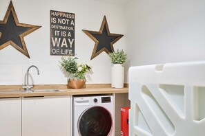 A kitchen with a washing machine, a sink, and decorative stars on the wall. - Host Stay Albert House (Weymouth)