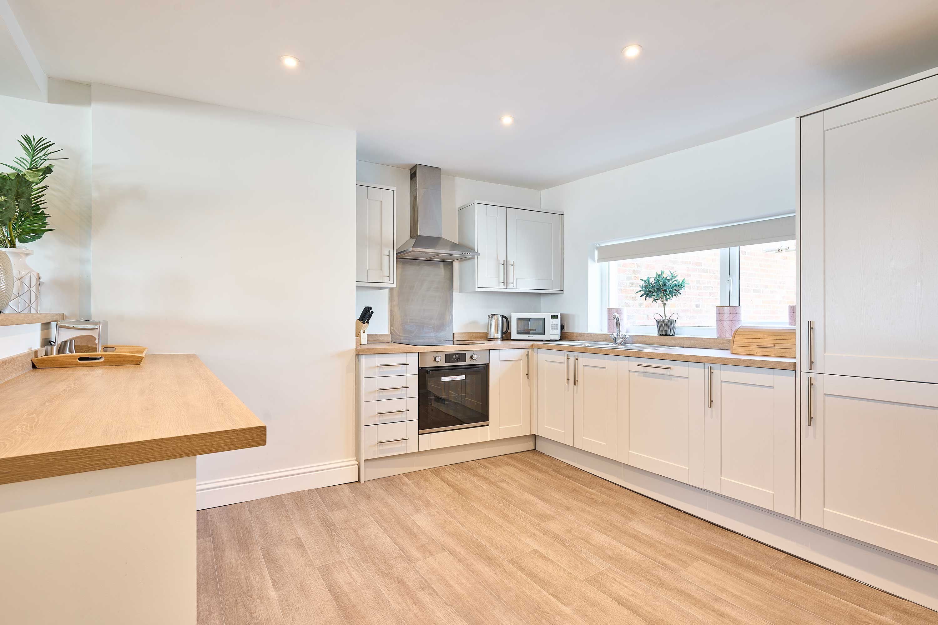 A modern kitchen with white cabinetry, a built-in oven, and a microwave.
