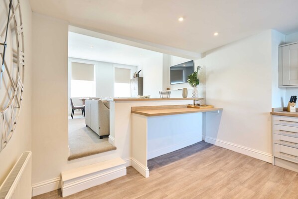 A modern kitchen with a wooden countertop, white cabinetry, and a built-in oven. - Host Stay Albert House (Weymouth)