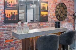 Et barområde med en murstensvæg, et stort ur og en bardisk med glas og en sort beholder mærket 'ice'.