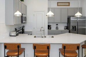 A modern kitchen with a central island, stainless steel appliances, and pendant lighting. - Near Theme Parks•Drive•Pvt Pool•Poker Room (Orlando)