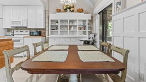 A dining area with a wooden table, four chairs, and a chandelier.