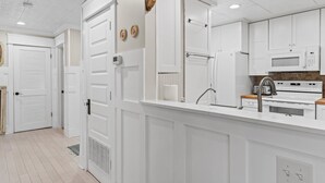 A modern kitchen with white cabinetry, a built-in microwave, and a stainless steel sink.