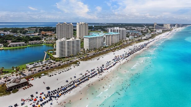 A coastal cityscape with a long beach, high-rise hotels, and a marina.