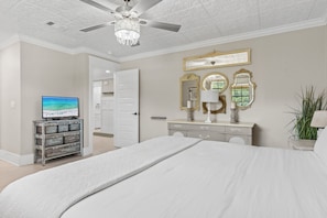 Relax in this stylish bedroom with a large bed, ceiling fan, and chandelier.