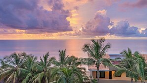 Une vue sur la côte, avec des palmiers et un bâtiment doté d’un toit en tuiles.