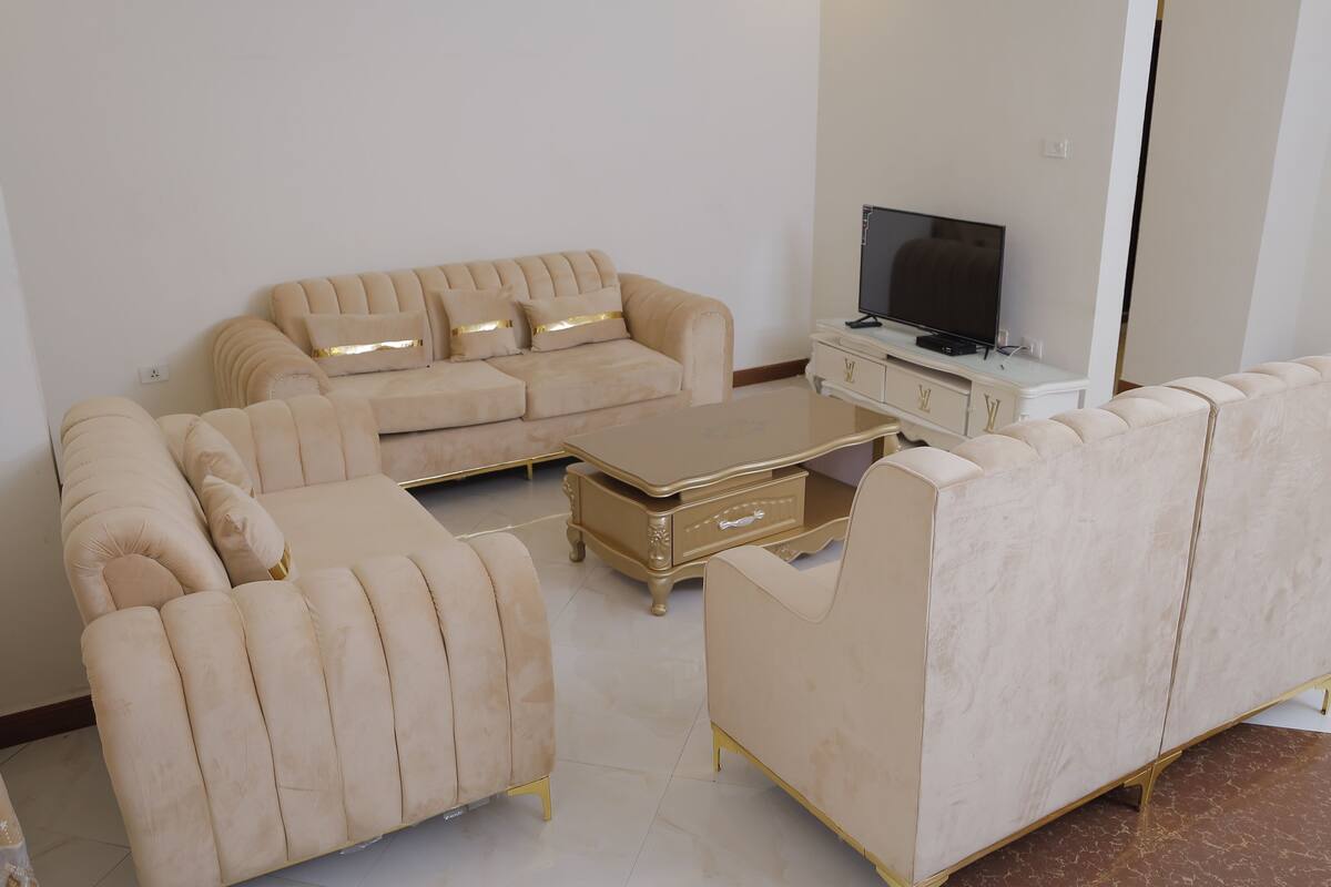 A living room with a beige sofa set, a coffee table, and a TV.