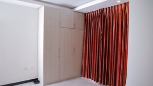 A room with a wooden wardrobe, a red curtain, and a white wall.
