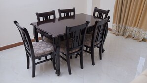 A round dining table with six chairs, each with a cushioned seat and backrest.