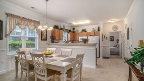 A modern kitchen with white cabinetry, a central island, and a dining area with a table and chairs.