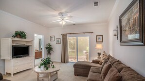 A living room with a television, sofa, and a ceiling fan.