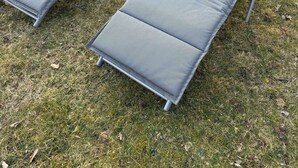Dos sillones reclinables con cojines y una pequeña mesa redonda con dos copas de vino.