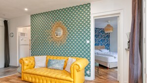 Un canapé jaune, un lit, un four à micro-ondes et un mur orné d’un motif texturé.