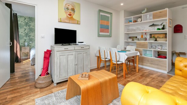 Un salon moderne avec un téléviseur, un coin repas et une bibliothèque.