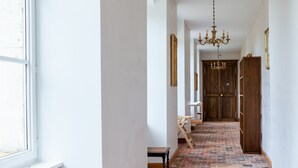 A hallway with a brick floor, white walls, a wooden door, and a chandelier. - Domaine 'Gîte De L'Abbaye' with Private Pool, Private Terrace and Wi-Fi (Rollainville)