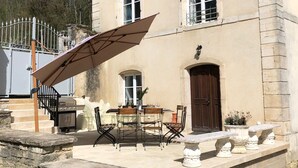 A two-story building with a stone facade, a balcony with a metal railing, and a dining area with a table and chairs. - Domaine 'Gîte De L'Abbaye' with Private Pool, Private Terrace and Wi-Fi (Rollainville)