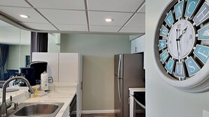 Une cuisine moderne dotée d’appareils électroménagers en acier inoxydable, d’un évier à deux bacs et d’une horloge murale originale.