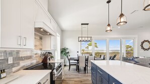 A modern kitchen with white cabinets, a large island, and a view of the beach. - 8 Minute Walk to Beach | Dogs Allowed (Port St. Joe)
