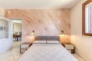 Una camera da letto con una parete in marmo, un letto con due cuscini, due comodini e una finestra.
