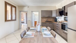 A modern kitchen with a dining area, featuring a wooden table set for four, a built-in oven, and a large window. - Villa 'Marilor' with Sea View, Wi-Fi, and Air Conditioning (Salve)