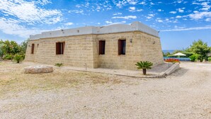 A stone building with a flat roof, rectangular windows, and a gravel driveway. - Villa 'Marilor' with Sea View, Wi-Fi, and Air Conditioning (Salve)