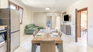 A modern kitchen with a built-in oven, a refrigerator, and a dining area with a table set for four. - Villa 'Marilor' with Sea View, Wi-Fi, and Air Conditioning (Salve)
