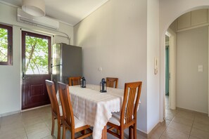 Un coin repas avec une table dressée pour quatre personnes, des chaises, un réfrigérateur et un appareil de climatisation.